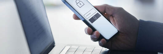 a person using a cellphone to unlock an app on a laptop