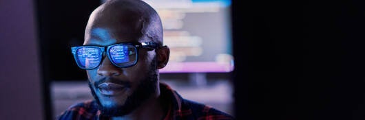 It specialist in glasses reviewing work on a monitor