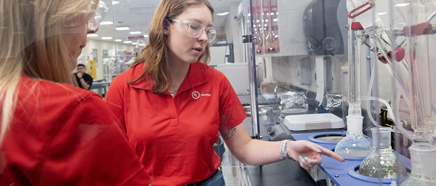 Two UL Solutions employees looking at a distilling beakers in a lab
